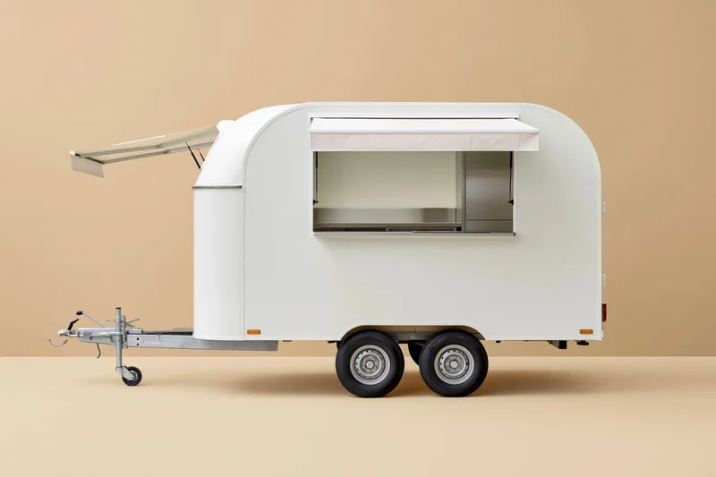 White food trailer with open service window and extended awning on beige background