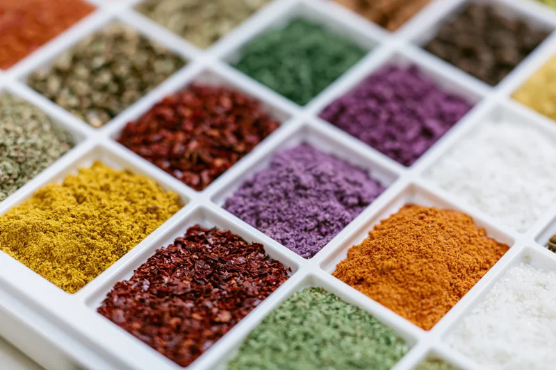 Colorful spices arranged in a white plastic tray grid for culinary display
