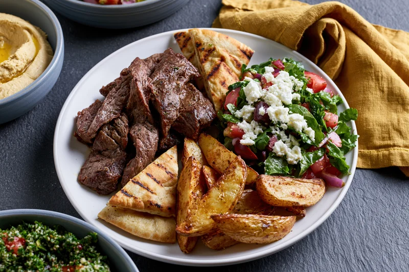 Plate of shawarma beef with grilled pita and salad on slate surface