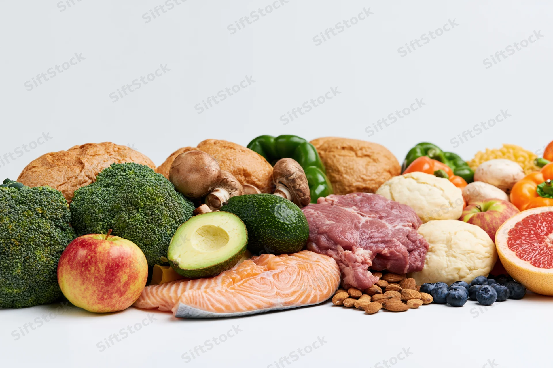 A wide spread of raw whole foods arranged in a low horizontal line on a white surface