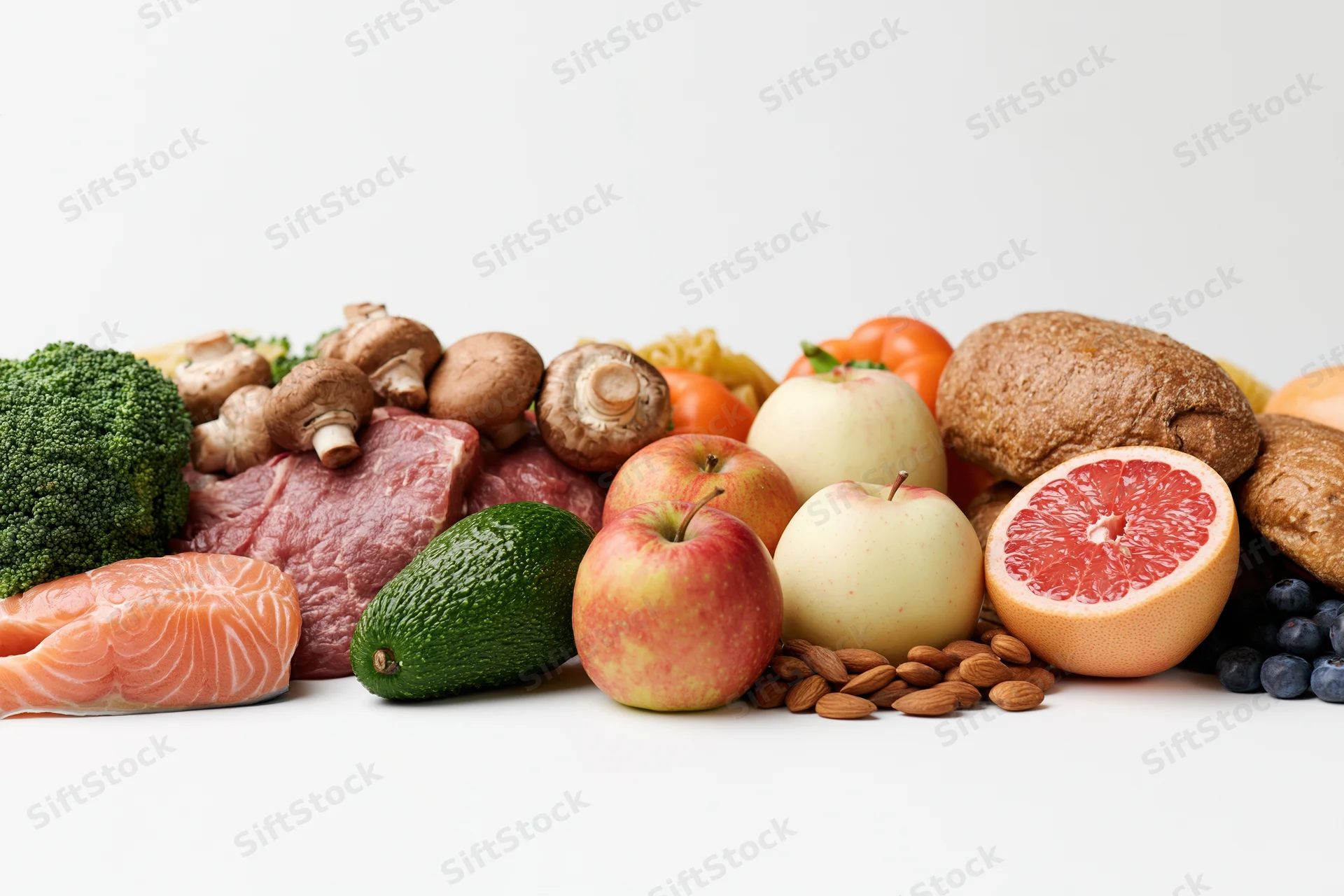 A wide spread of raw whole foods arranged in a low horizontal line on a white surface