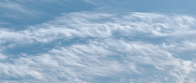 Aerial view of wispy white cirrus clouds against a pale blue sky