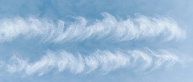 Aerial view of wispy white cirrus clouds against a pale blue sky