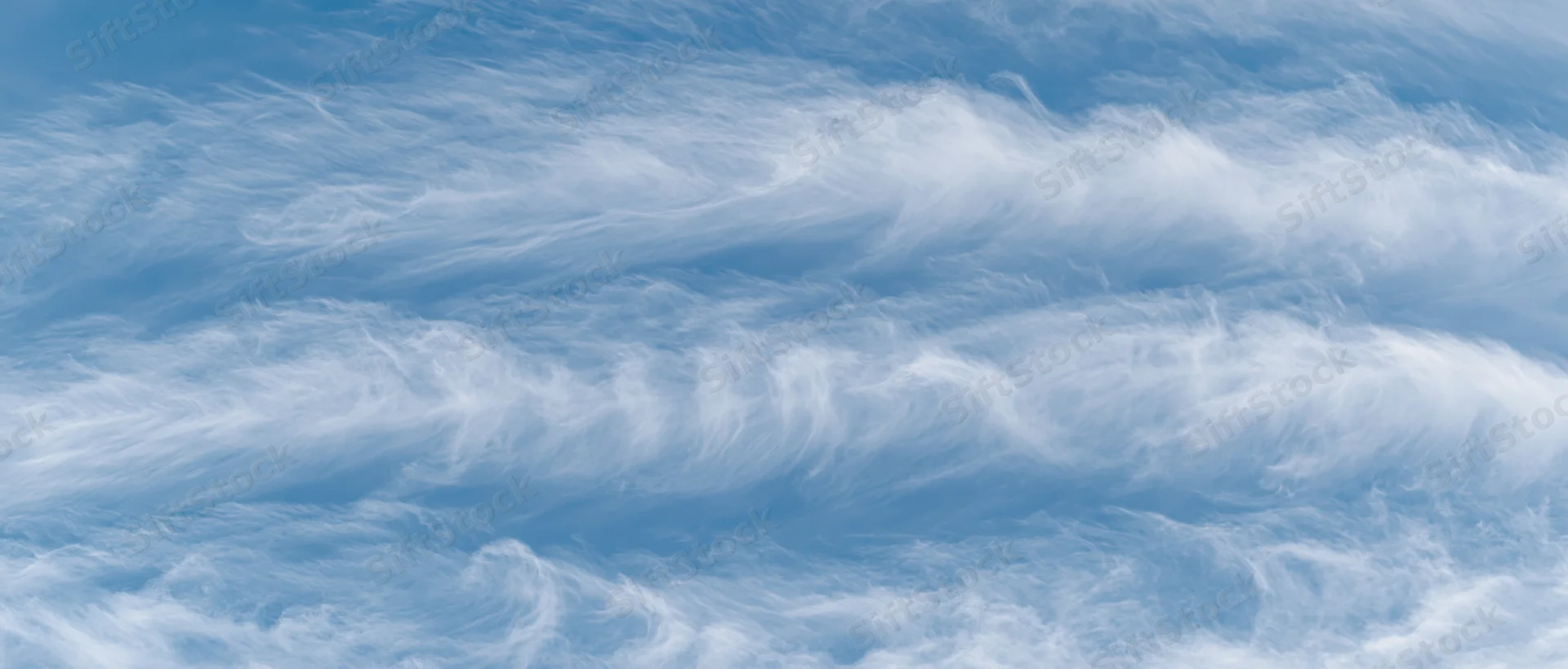Aerial view of wispy white cirrus clouds against a pale blue sky
