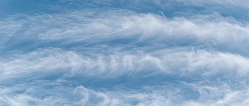 Aerial view of wispy white cirrus clouds against a pale blue sky