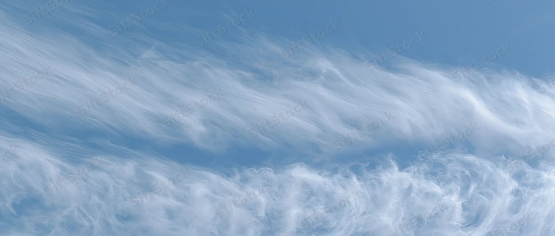 Aerial view of wispy white clouds against a pale blue sky