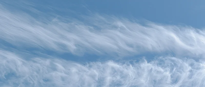 Aerial view of wispy white clouds against a pale blue sky
