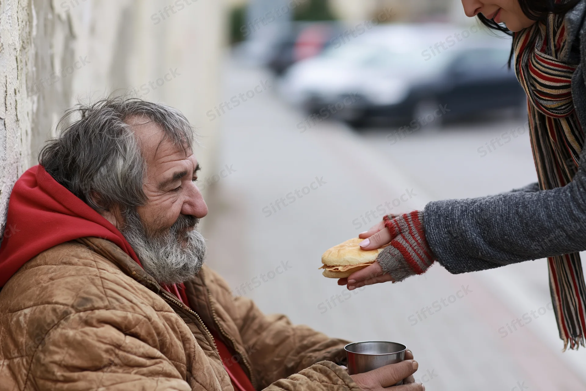 Elderly homeless man receiving sandwich from woman on sidewalk