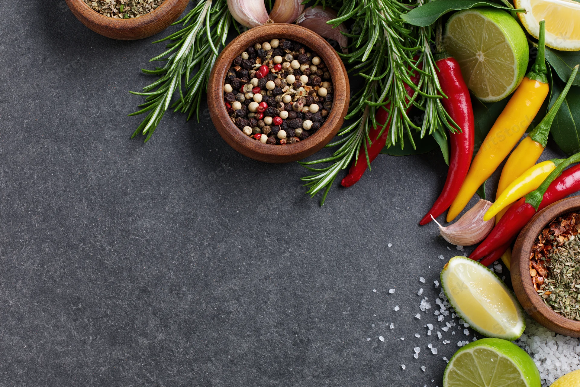 Fresh herbs and spices arranged along the right edge of a dark countertop
