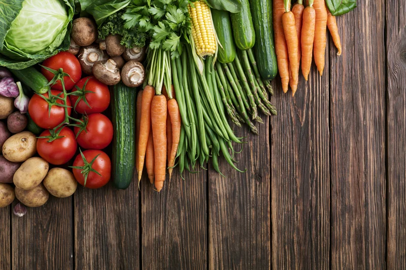 Fresh vegetables arranged in a row on a dark wooden surface