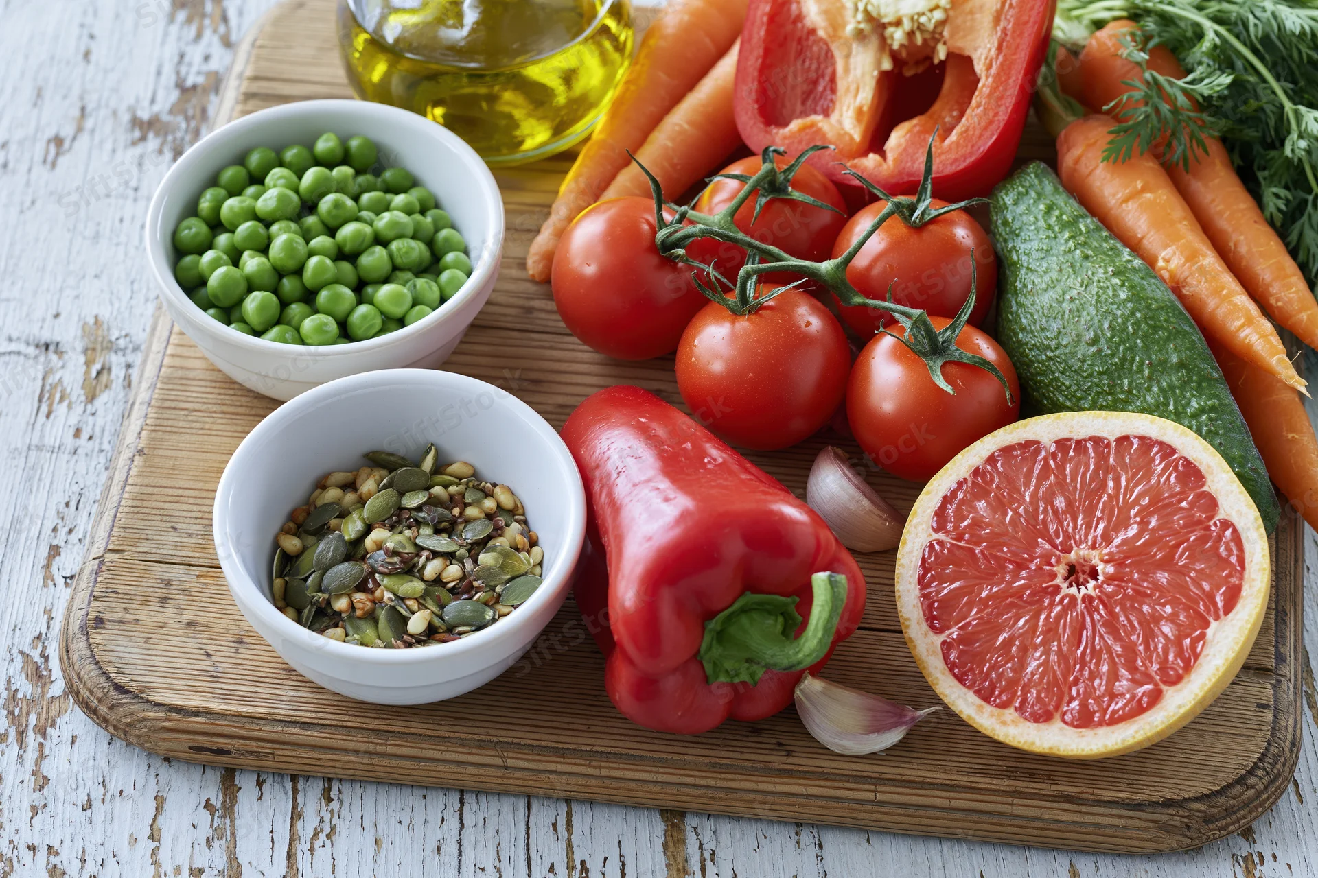 Fresh vegetables and fruits with seeds and olive oil arranged on a bamboo cutting board