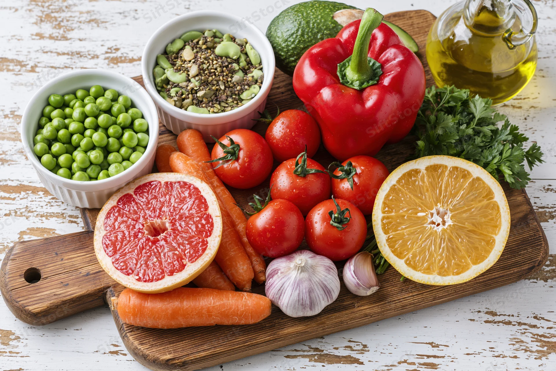 Fresh vegetables and fruits with seeds and olive oil arranged on a wooden cutting board