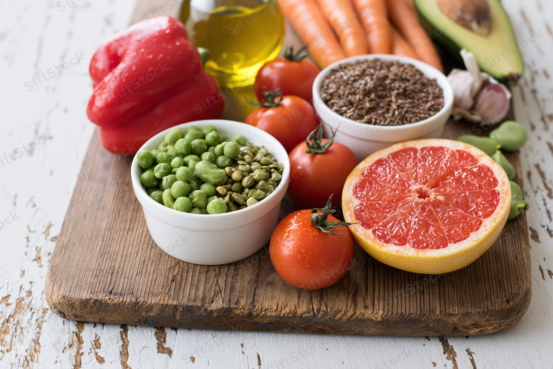 Fresh vegetables fruits seeds and olive oil arranged on a wooden cutting board