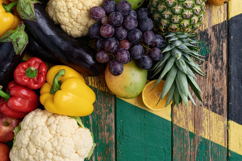 Fresh vegetables and tropical fruits arranged on a colorful wooden surface