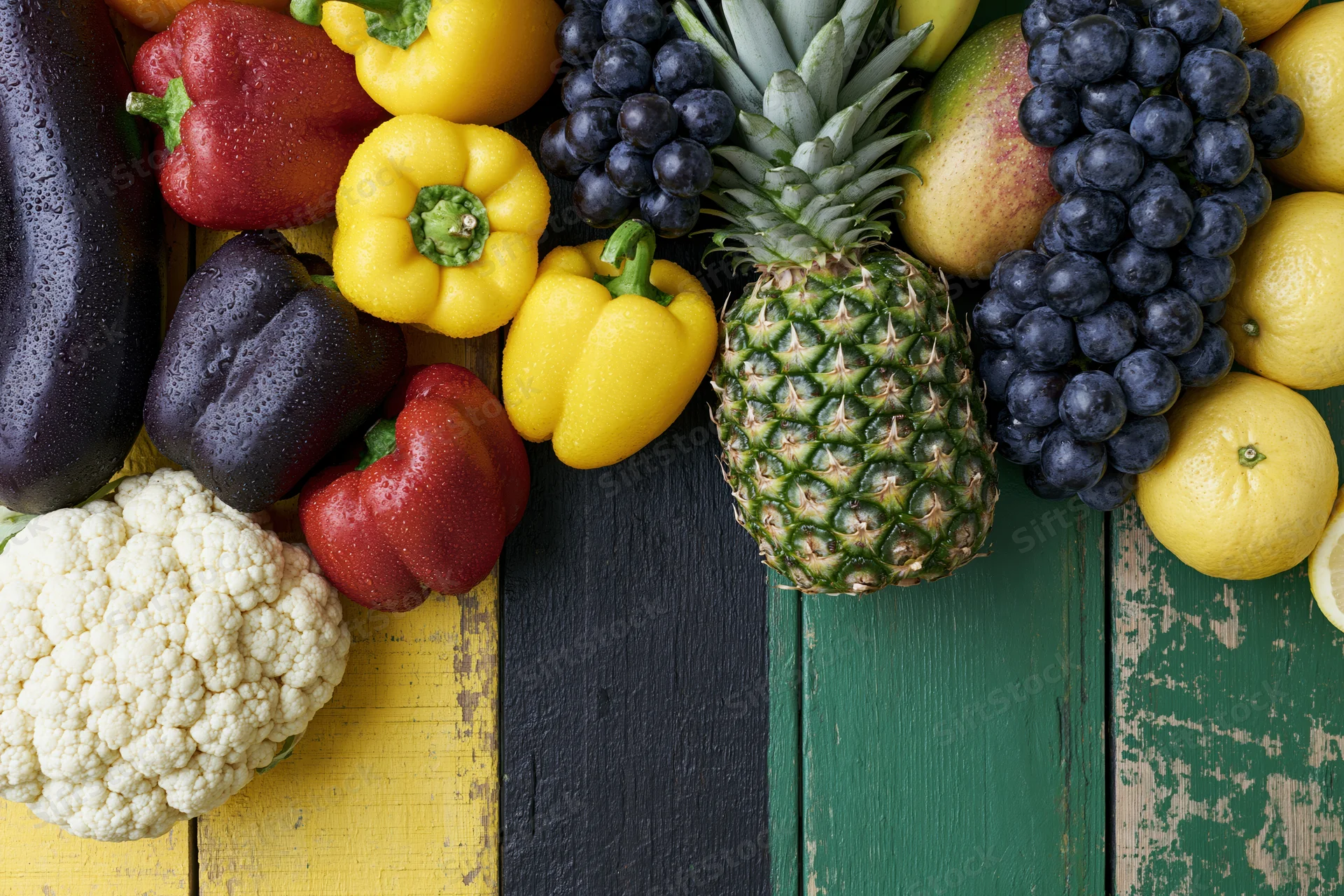 Fresh vegetables and tropical fruits arranged on a colorful wooden surface