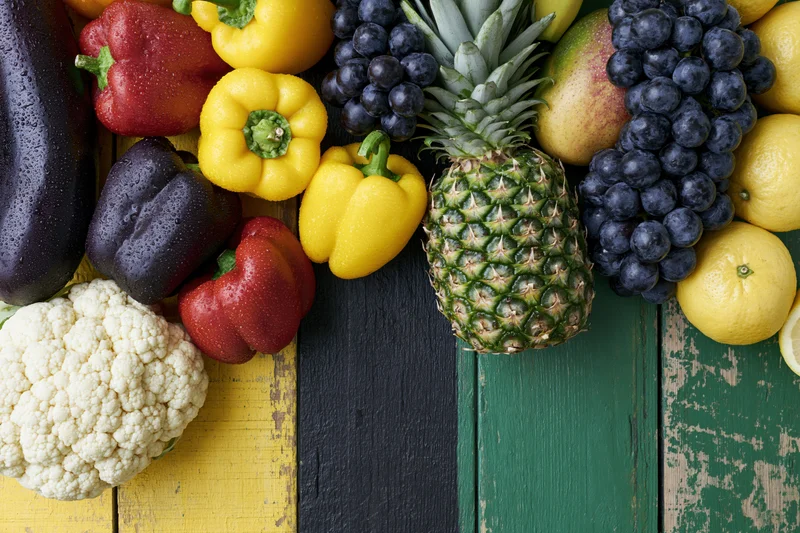 Fresh vegetables and tropical fruits arranged on a colorful wooden surface