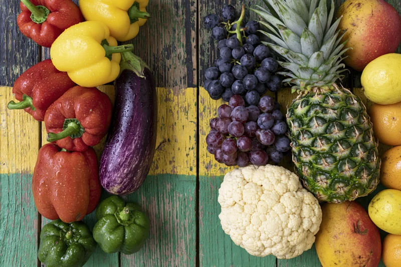 Fresh vegetables and tropical fruits arranged on a colorful wooden table in a flat lay view