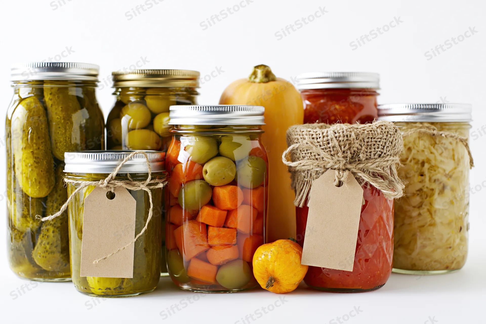 Glass jars filled with pickled and fermented vegetables arranged on a white surface