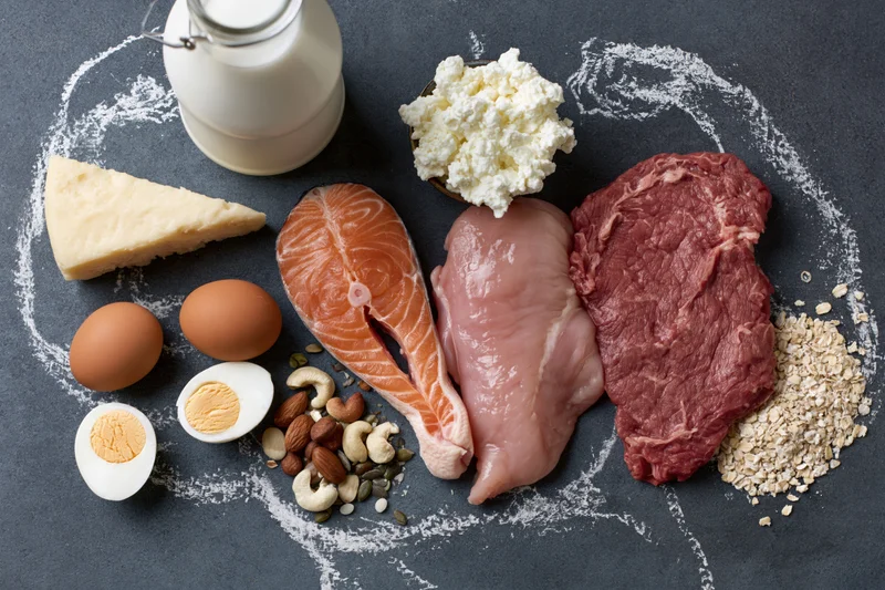High-protein foods arranged in a circle on dark chalkboard surface