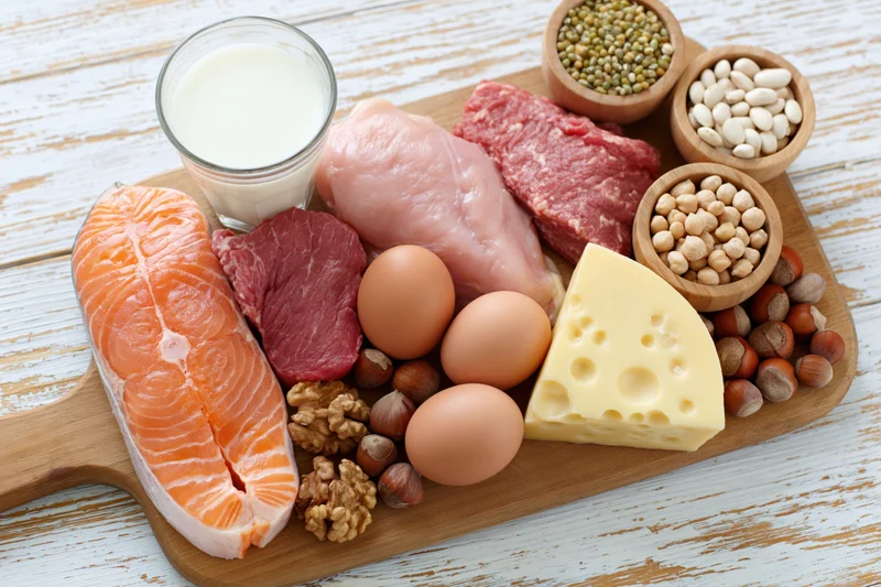 High-protein foods arranged on a wooden cutting board on a white rustic table