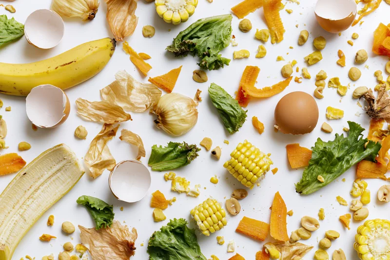 Assorted kitchen food scraps scattered on a white surface