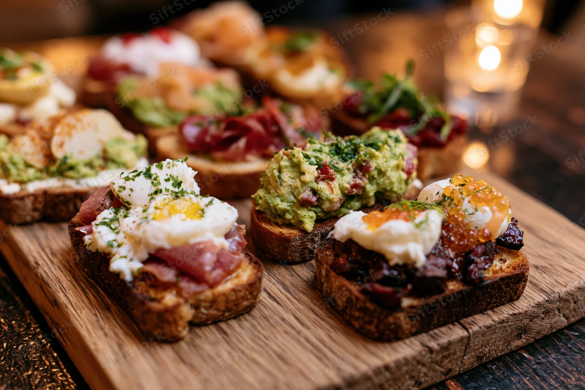 Assorted open-faced mini toasts with toppings arranged on a wooden board