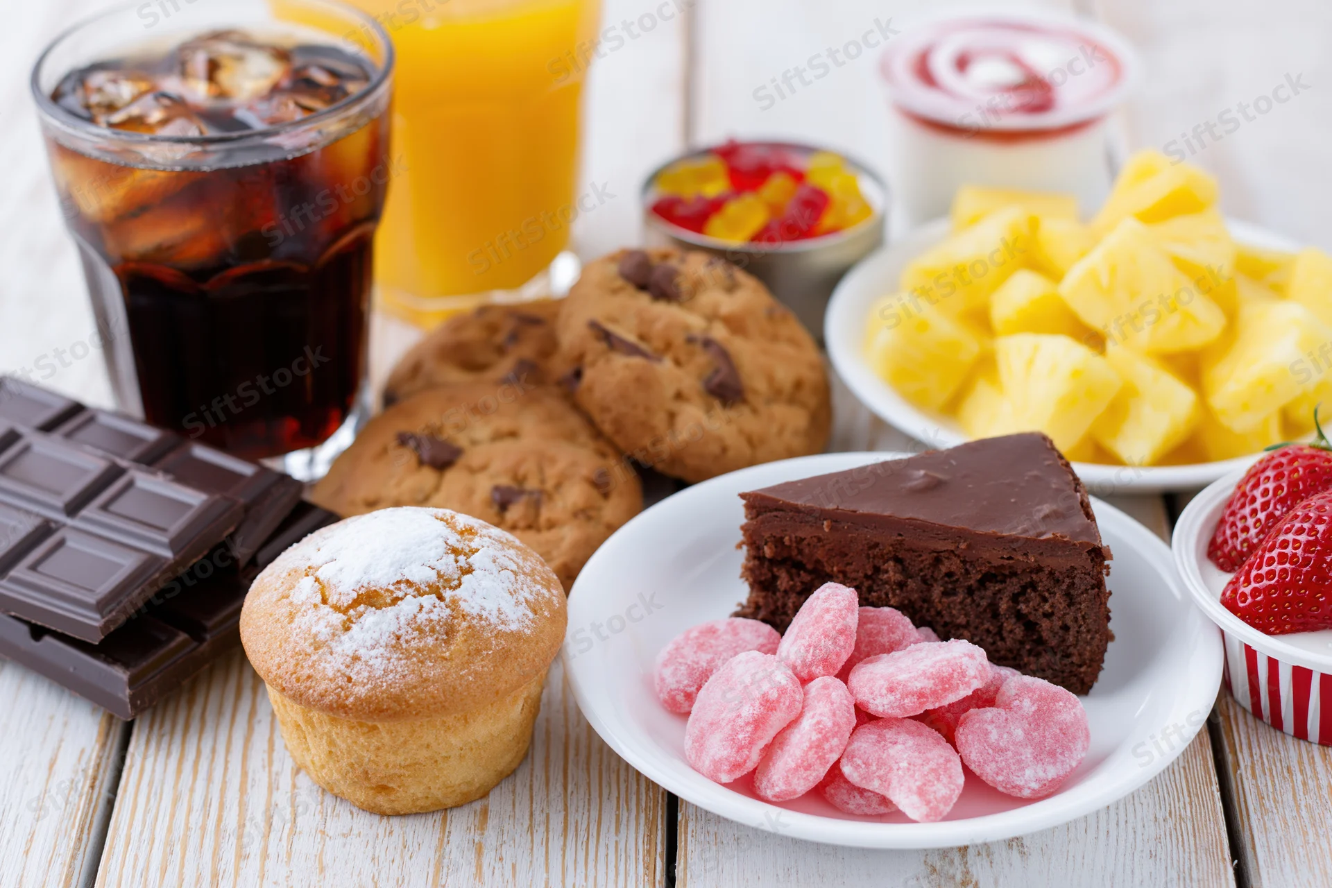 Assorted sugary foods and drinks arranged on a white painted wooden table