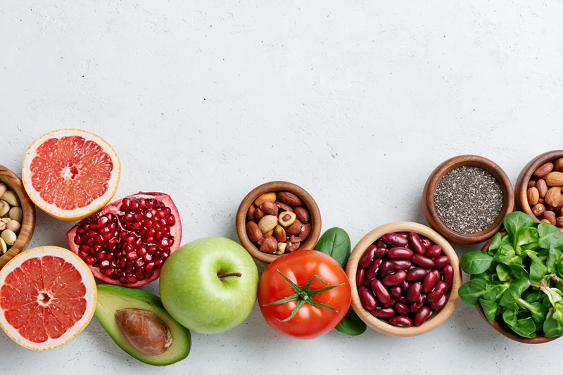 Assorted superfoods and fresh produce arranged in wooden bowls on a white surface