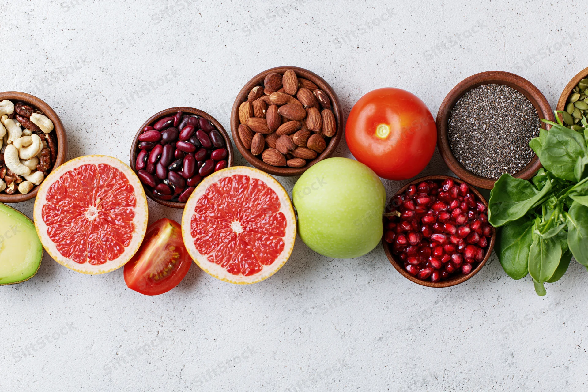 Assorted superfoods and fresh produce arranged in bowls and halves on a white countertop