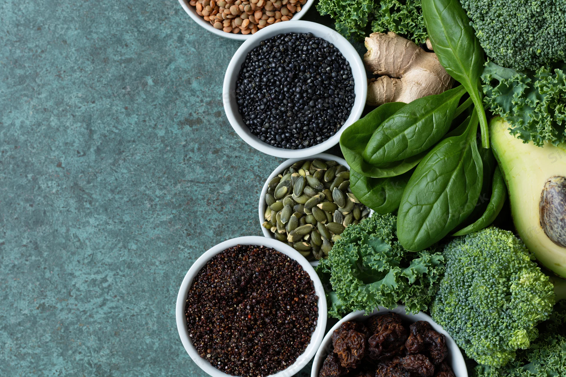 Superfoods and vegetables arranged along the right side of a textured blue surface with copyspace on the left