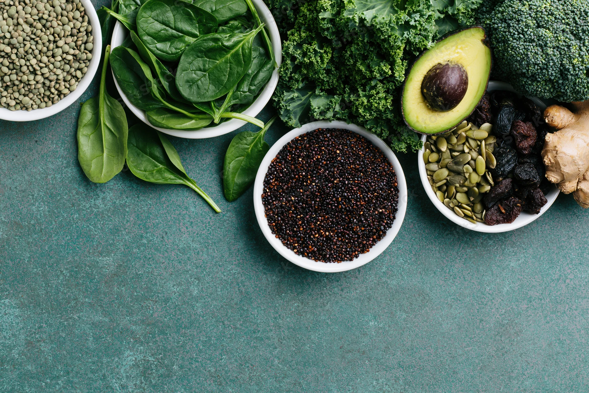 Assorted superfoods and vegetables arranged along the right edge of a textured surface with copyspace below