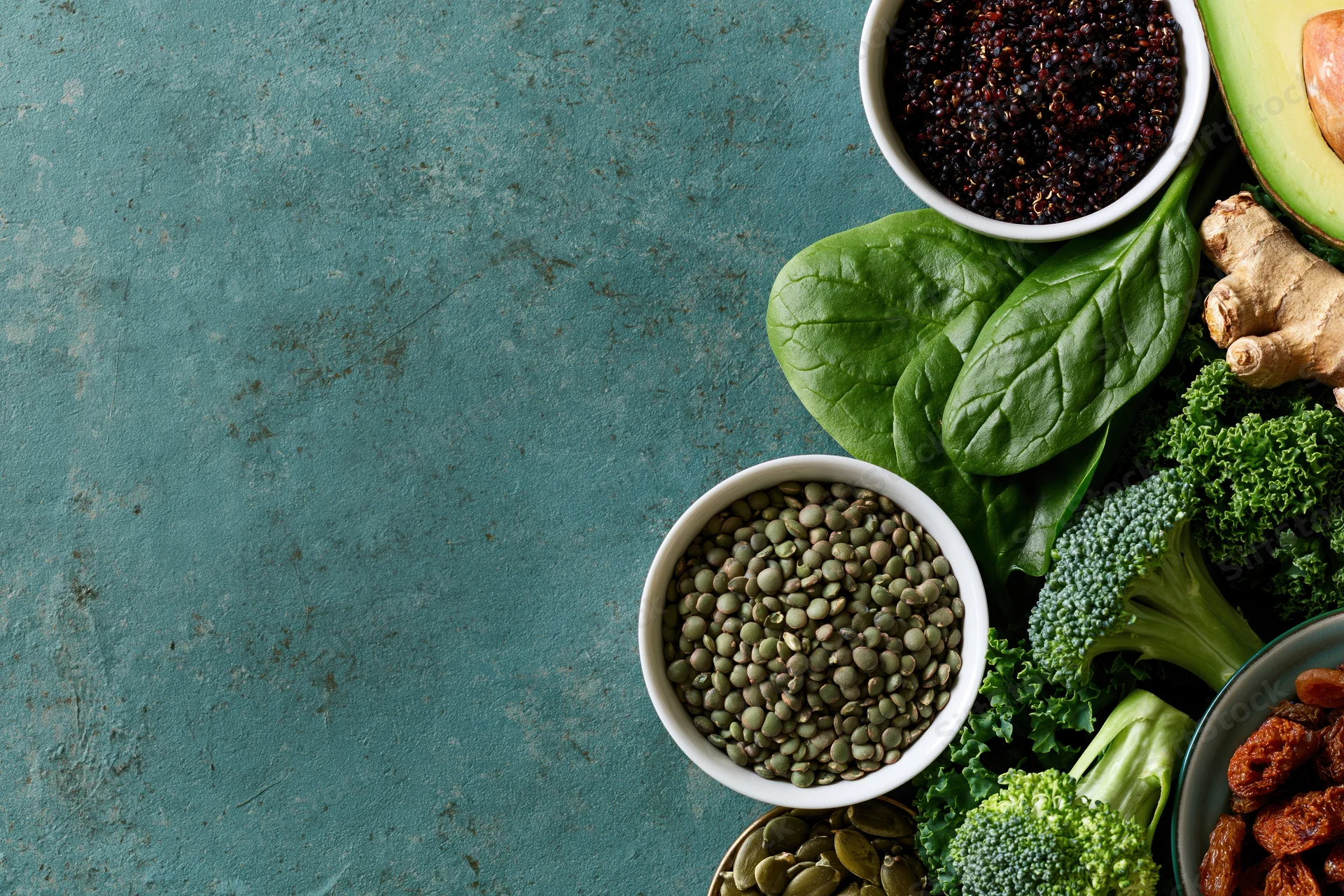 Assorted superfoods and vegetables arranged along the right side of a textured countertop