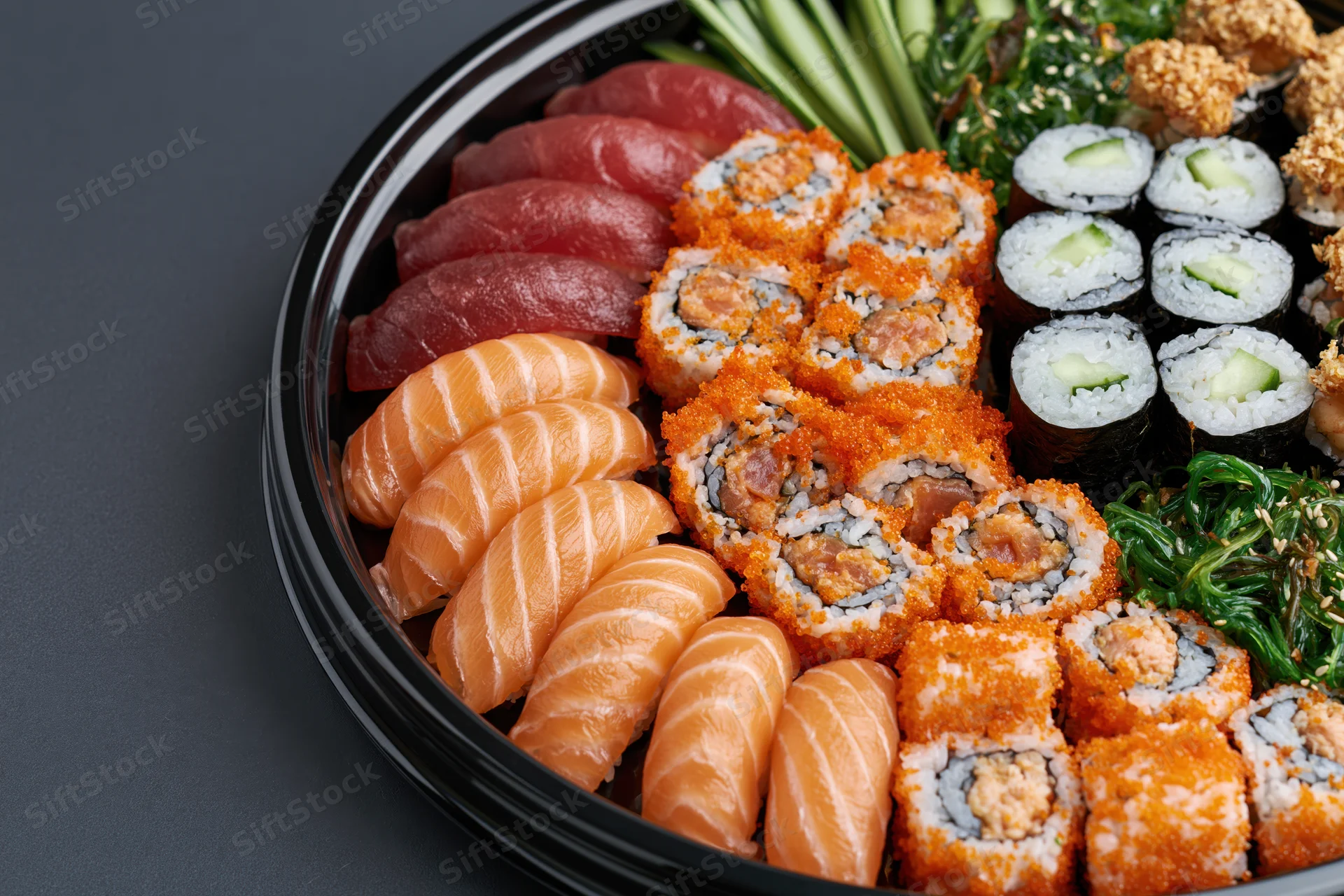 Assorted sushi platter with sashimi and maki rolls arranged on a black lacquer tray