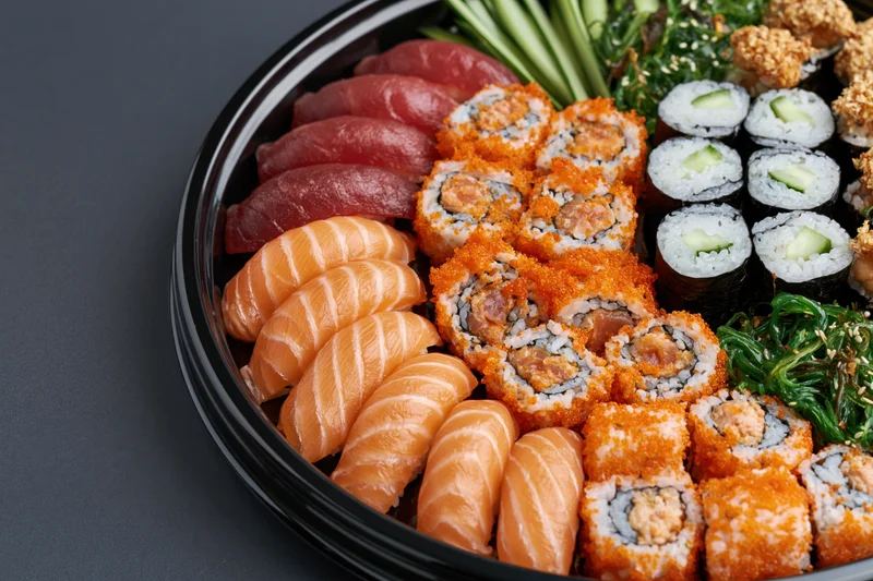 Assorted sushi platter with sashimi and maki rolls arranged on a black lacquer tray