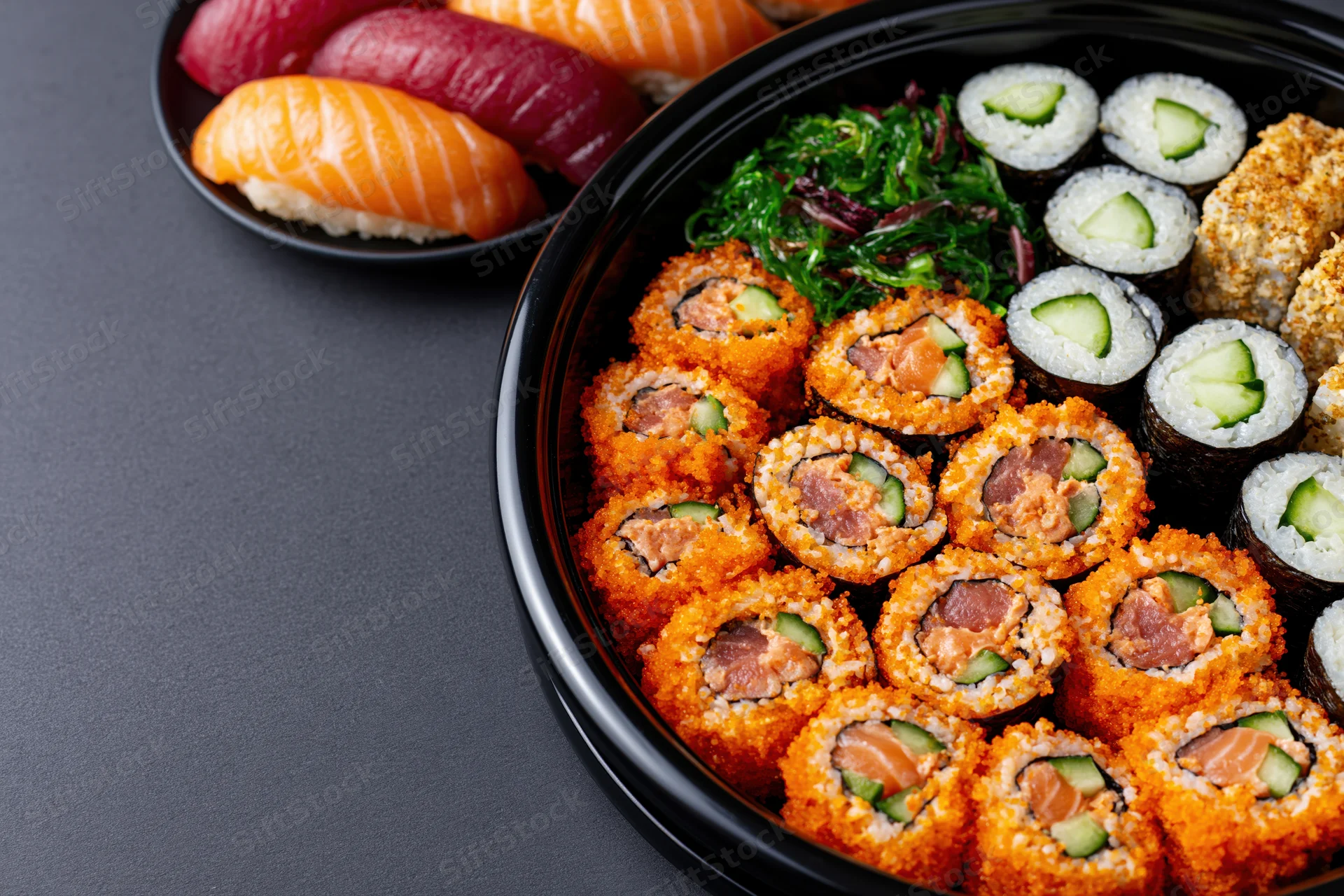 Assorted sushi platter with nigiri and rolls arranged on a round black lacquer tray