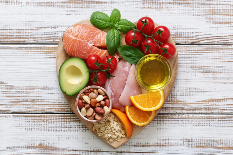 Heart-shaped arrangement of fresh whole foods on a wooden cutting board