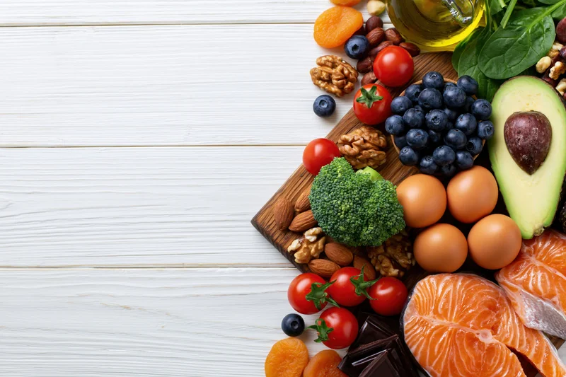 Healthy whole foods arranged on wooden board with white background and copyspace