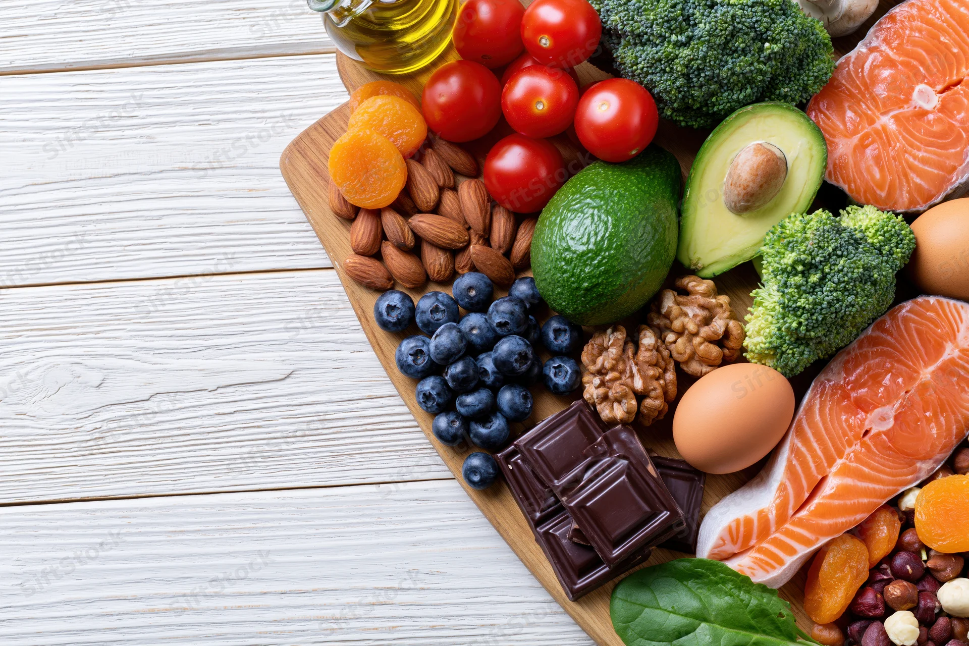 Variety of whole foods arranged on wooden board with white background and copyspace