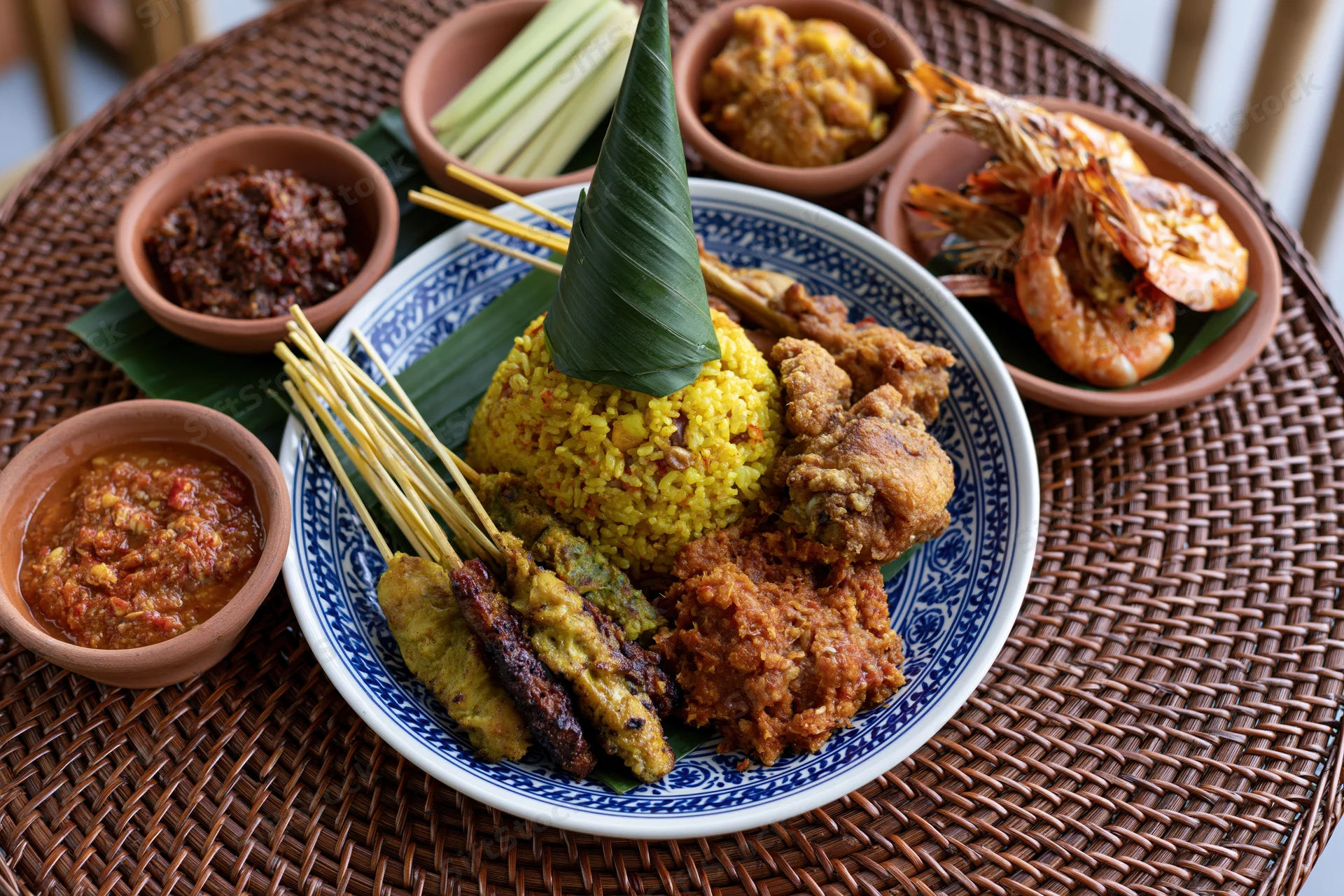 Balinese nasi kuning feast with satay and sambal on a woven rattan mat