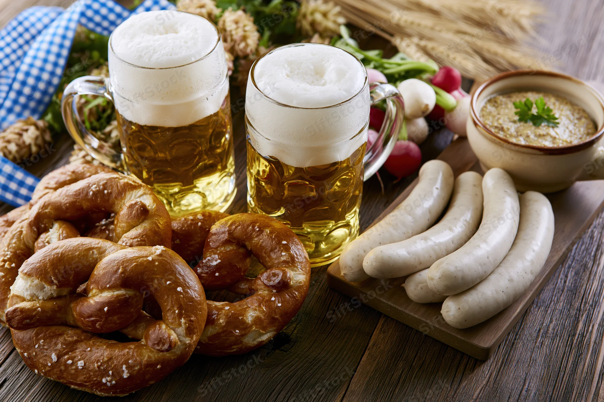Bavarian food spread with beer mugs, pretzels, sausages and soup on a rustic wooden table