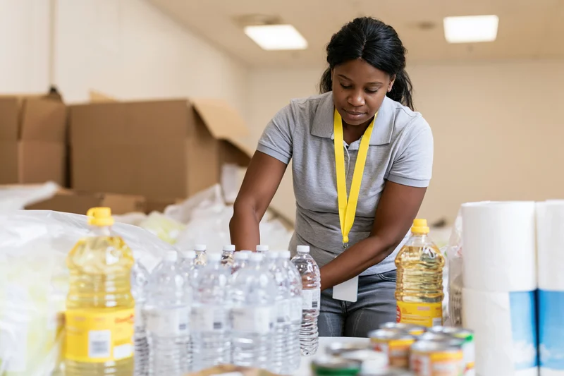 Black woman volunteer sorting bottled water and food supplies in a warehouse