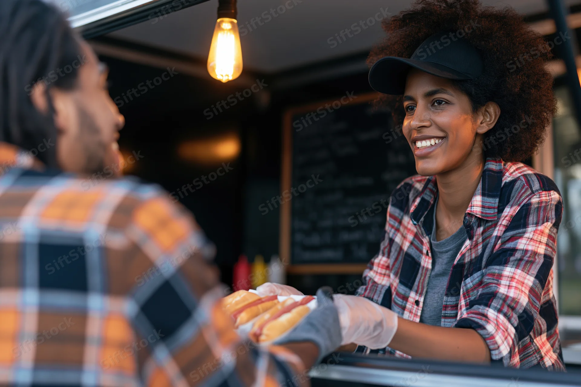 Woman serving hotdogs from a food truck to a customer