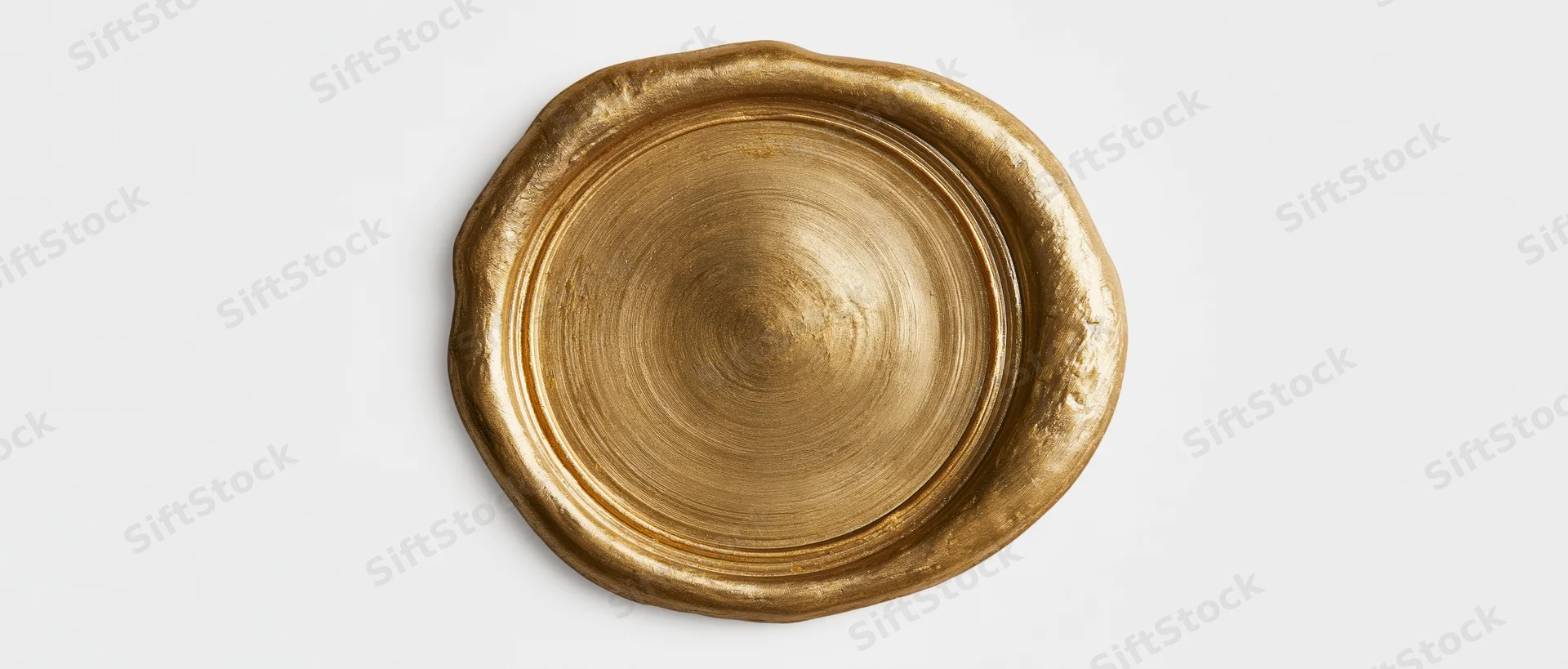 Gold wax seal with irregular melted edges on white background
