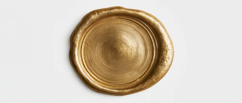 Gold wax seal with irregular melted edges on white background