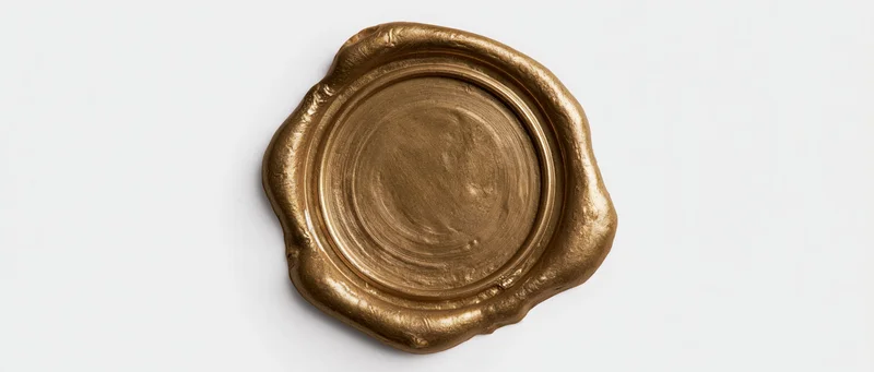 Gold wax seal with irregular melted edges on white background