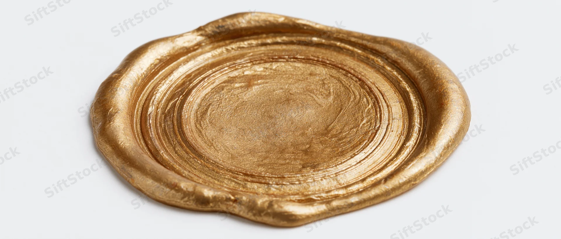 Gold wax seal with irregular melted edges and smooth surface on white background
