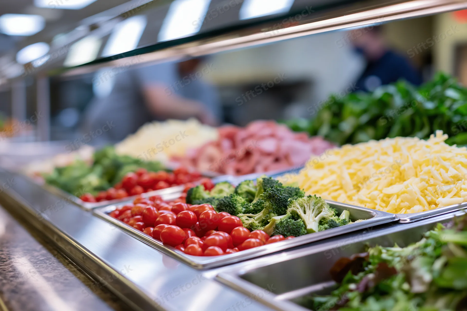Stainless steel trays filled with fresh vegetables and cheese at a cafeteria salad bar