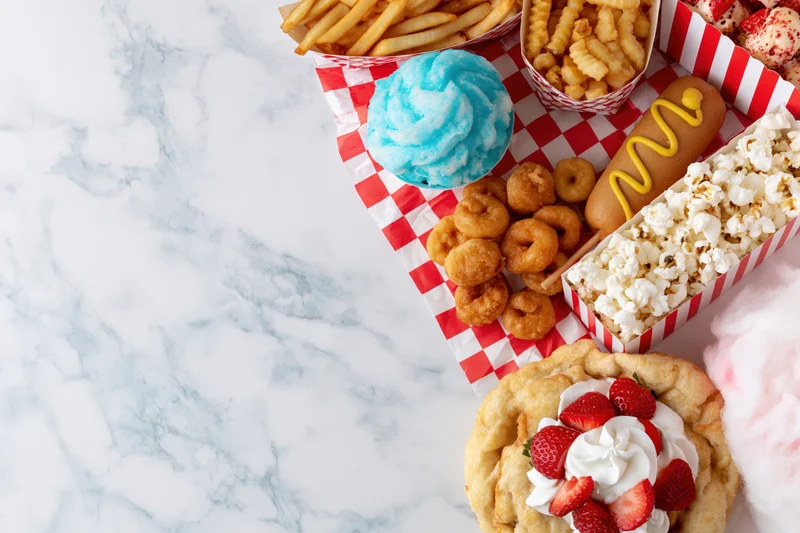 Carnival fair food spread arranged along right edge of marble countertop with copyspace on left