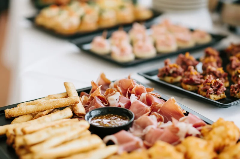 Catered buffet spread with charcuterie board and fries on black trays arranged on a white table