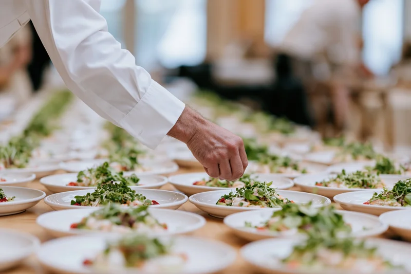 Chef garnishing rows of plated salads on a dining table